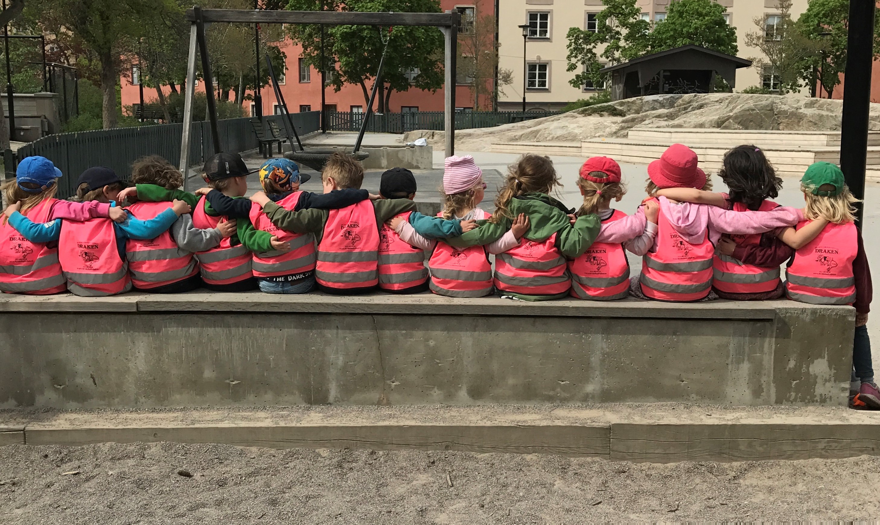 Barnen sitter i en rad och håller om varandra