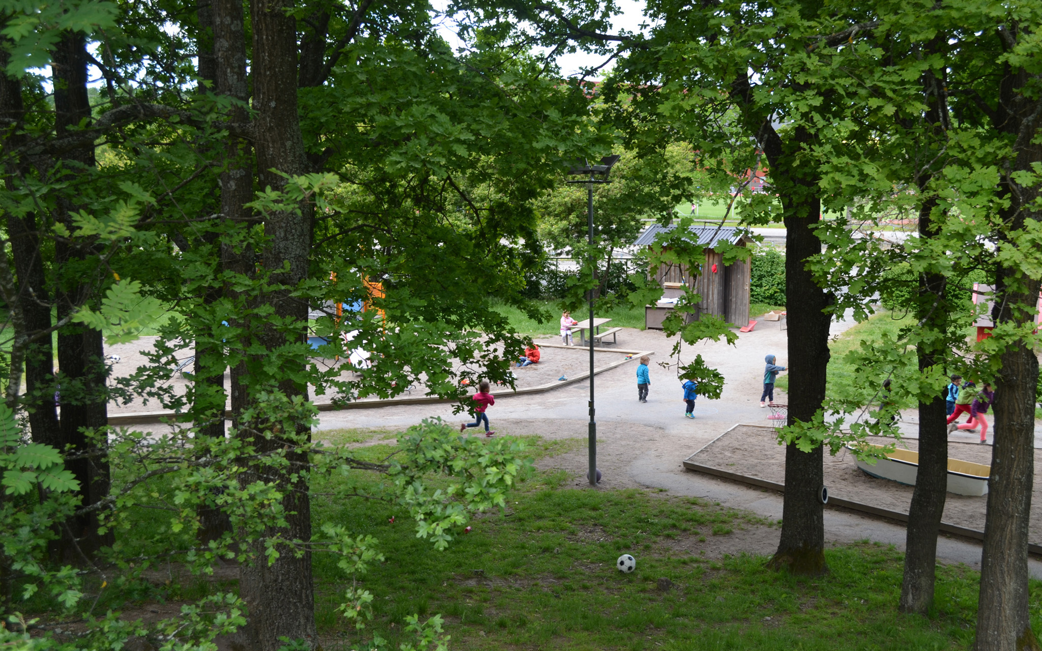 Bilden visar vår ljusa, gröna och stora innergård som erbjuder fina lekytor, lekutrustning och material för aktiva lekar.