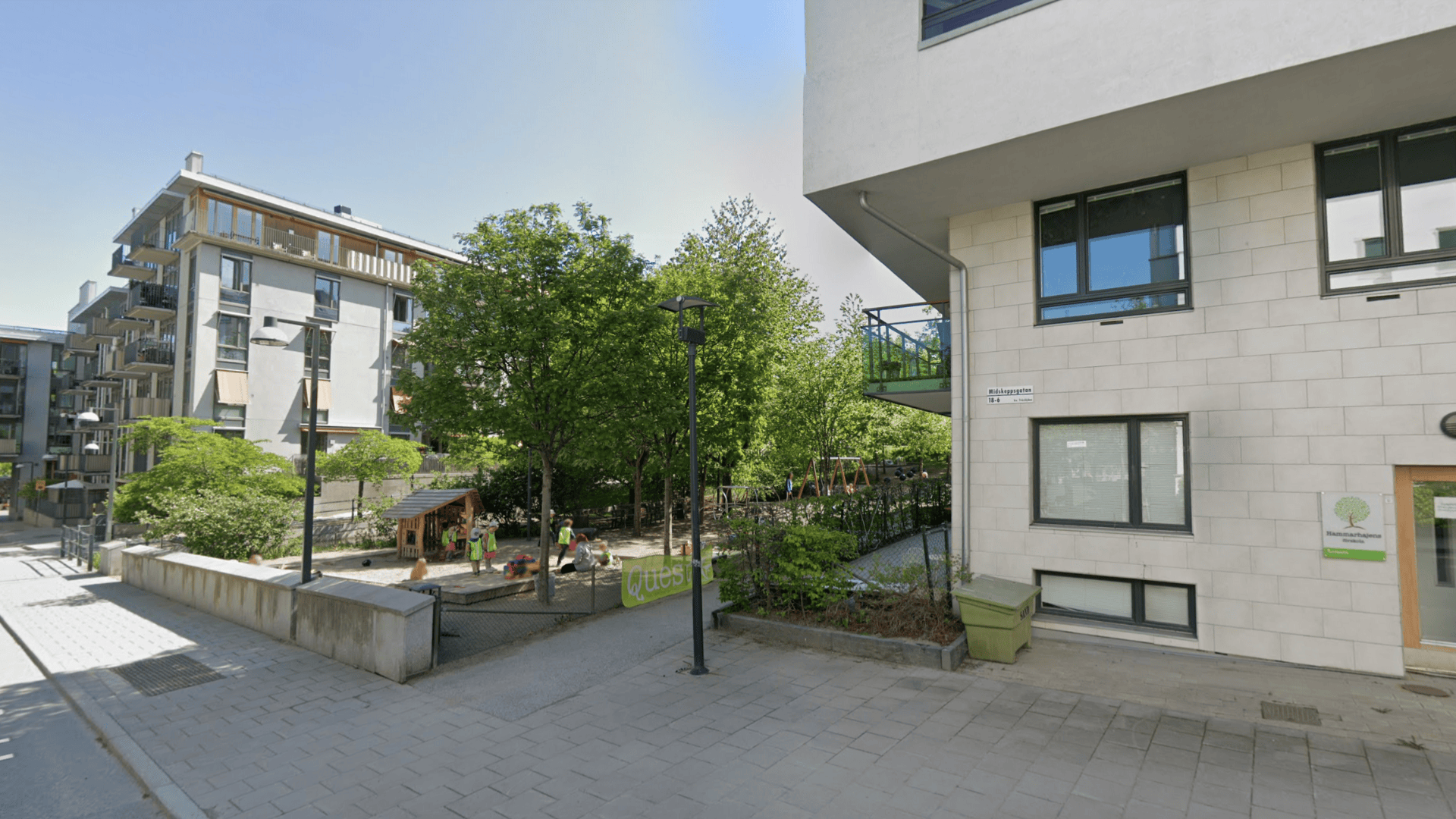 Fasad på vit byggnad som ligger intill en park, foto.