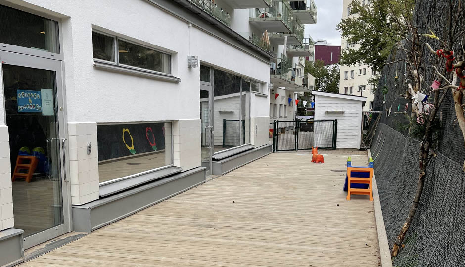 Lokal med vit fasad och trädäck utanför.