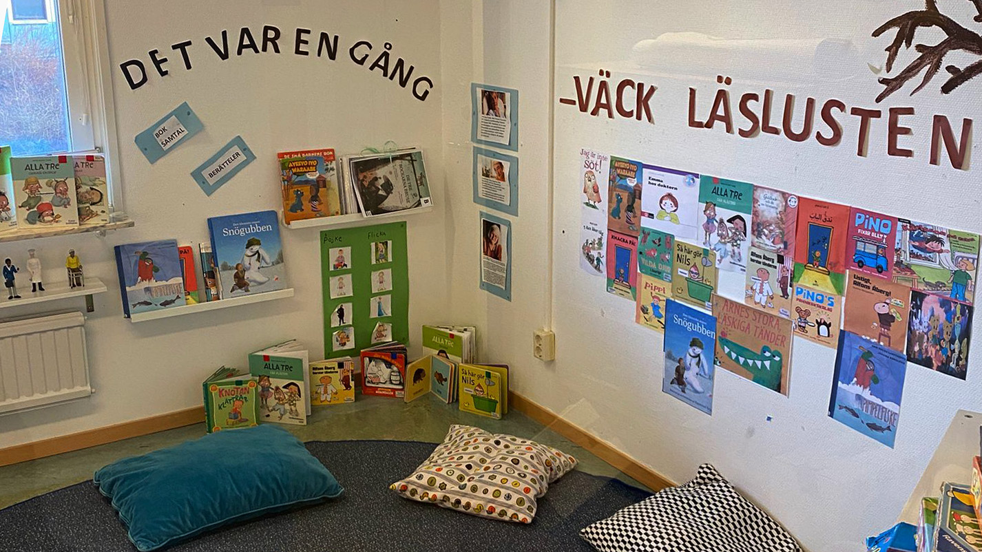 Läshörna med kuddar på golvet och hyllor med böcker.