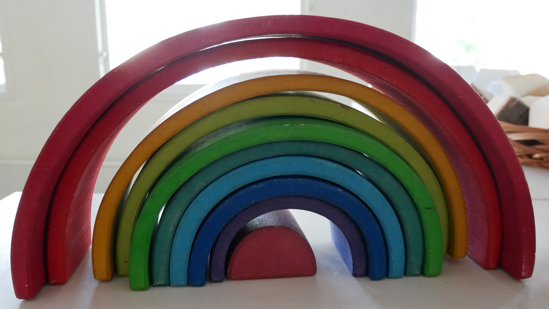 Färgglad regnbåge i trä som pedagogiskt lekmaterial på bord i förskolan.