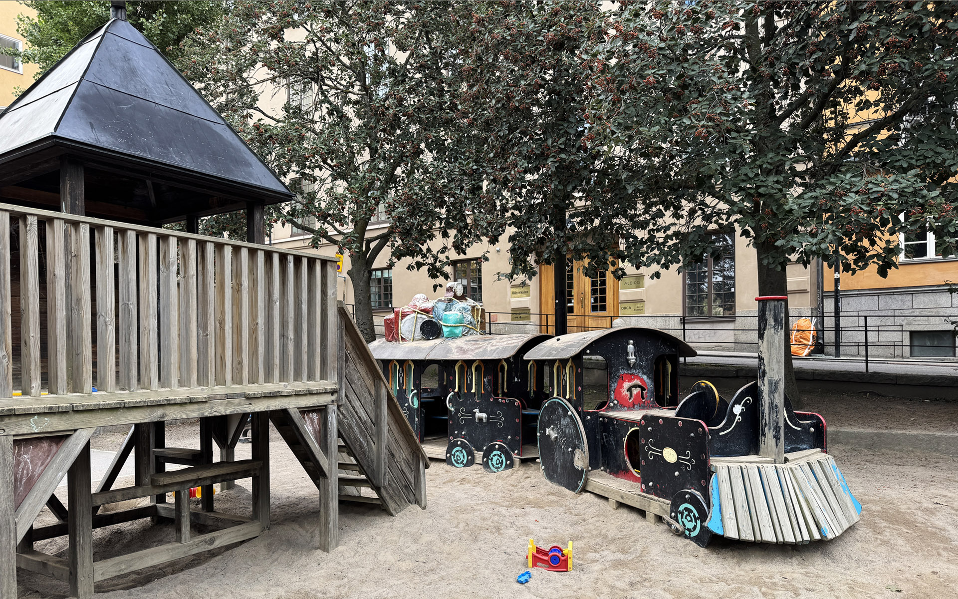 En lekpark med lekredskap i form av ett tåg och ett hus.