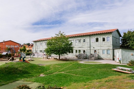 Grön förskolebyggnad på grästomt