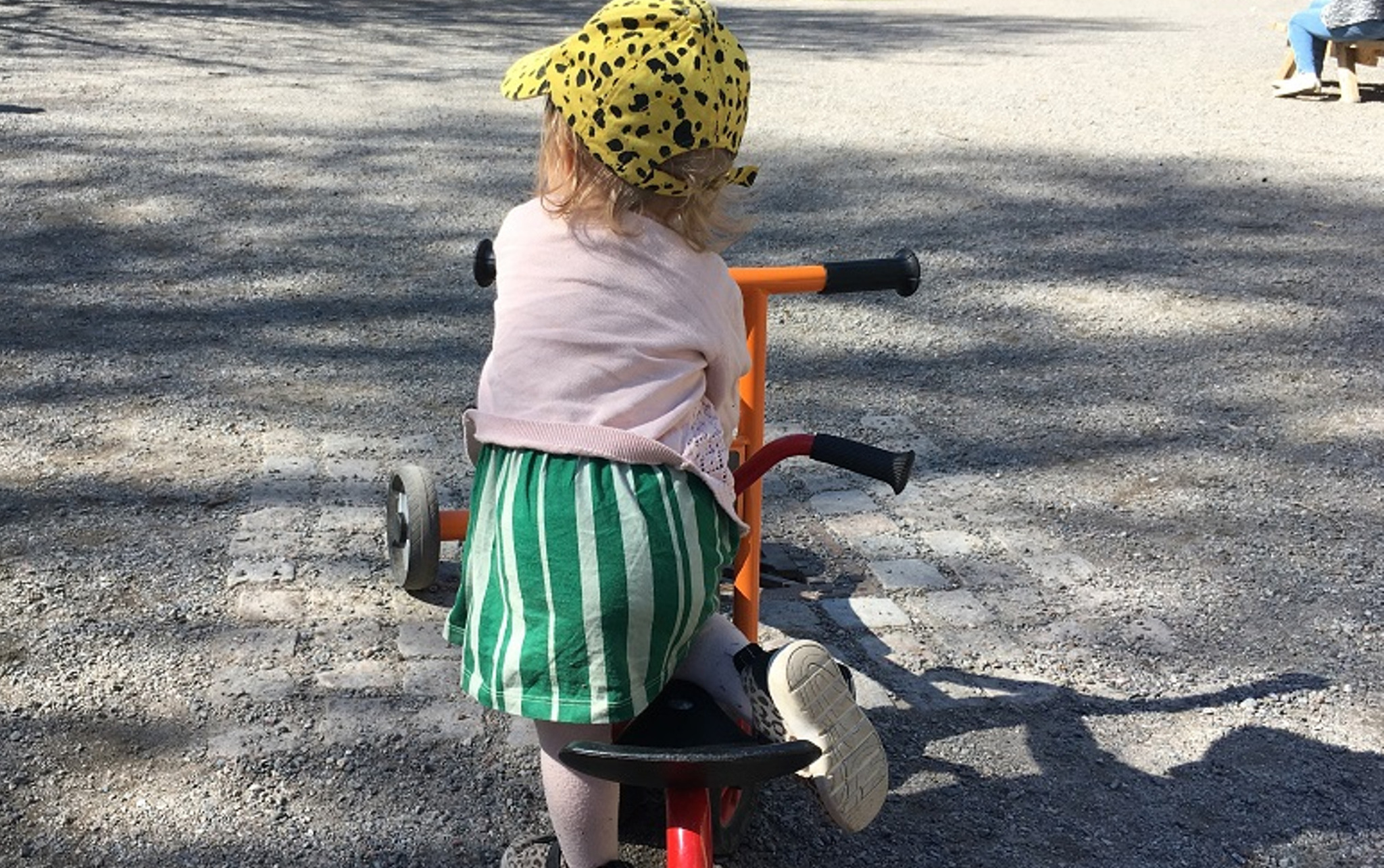 Ett yngre barn som cyklar utomhus i parkleken.
