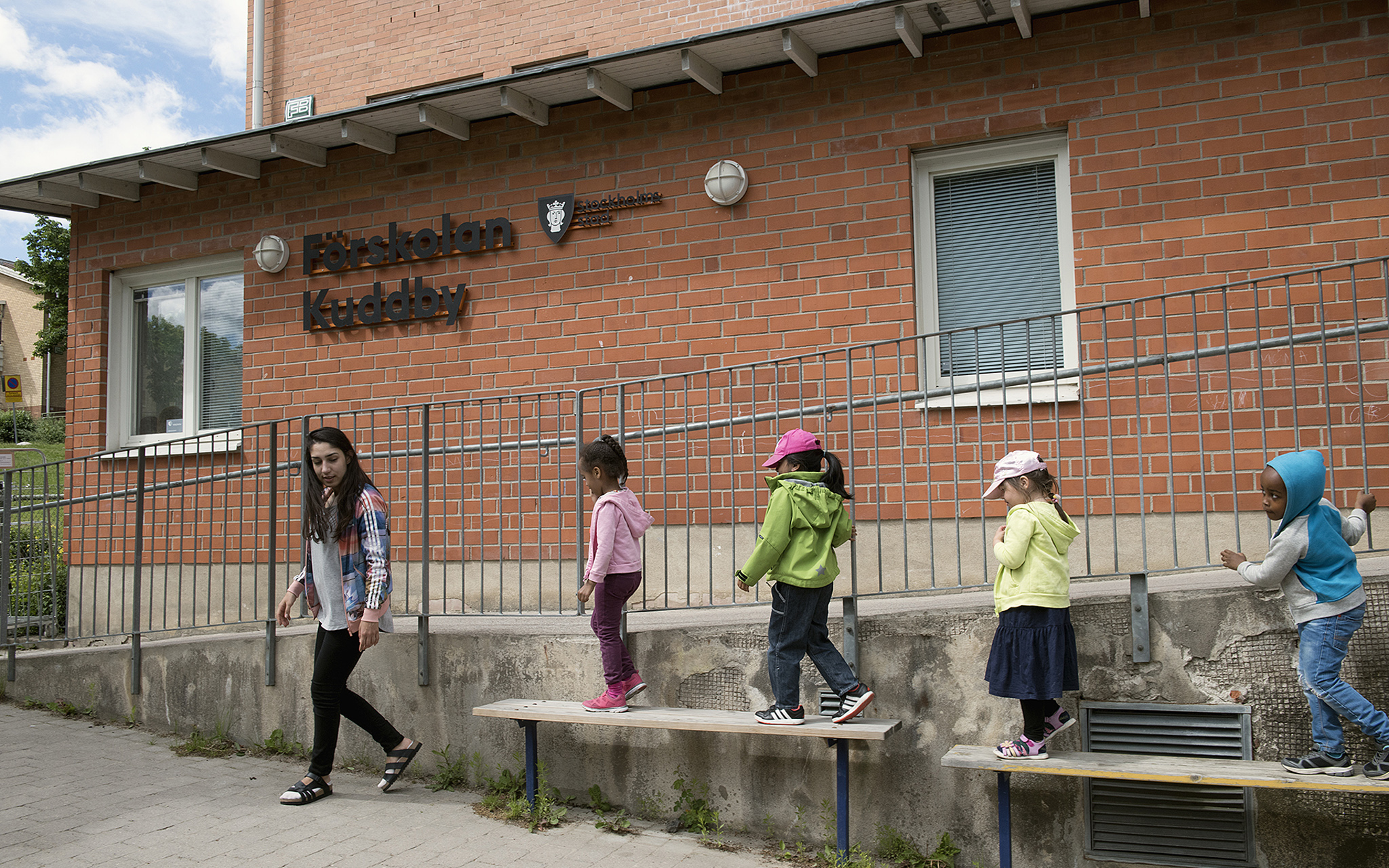 Barnen leker Följa John framför förskolan med en pedagog.
