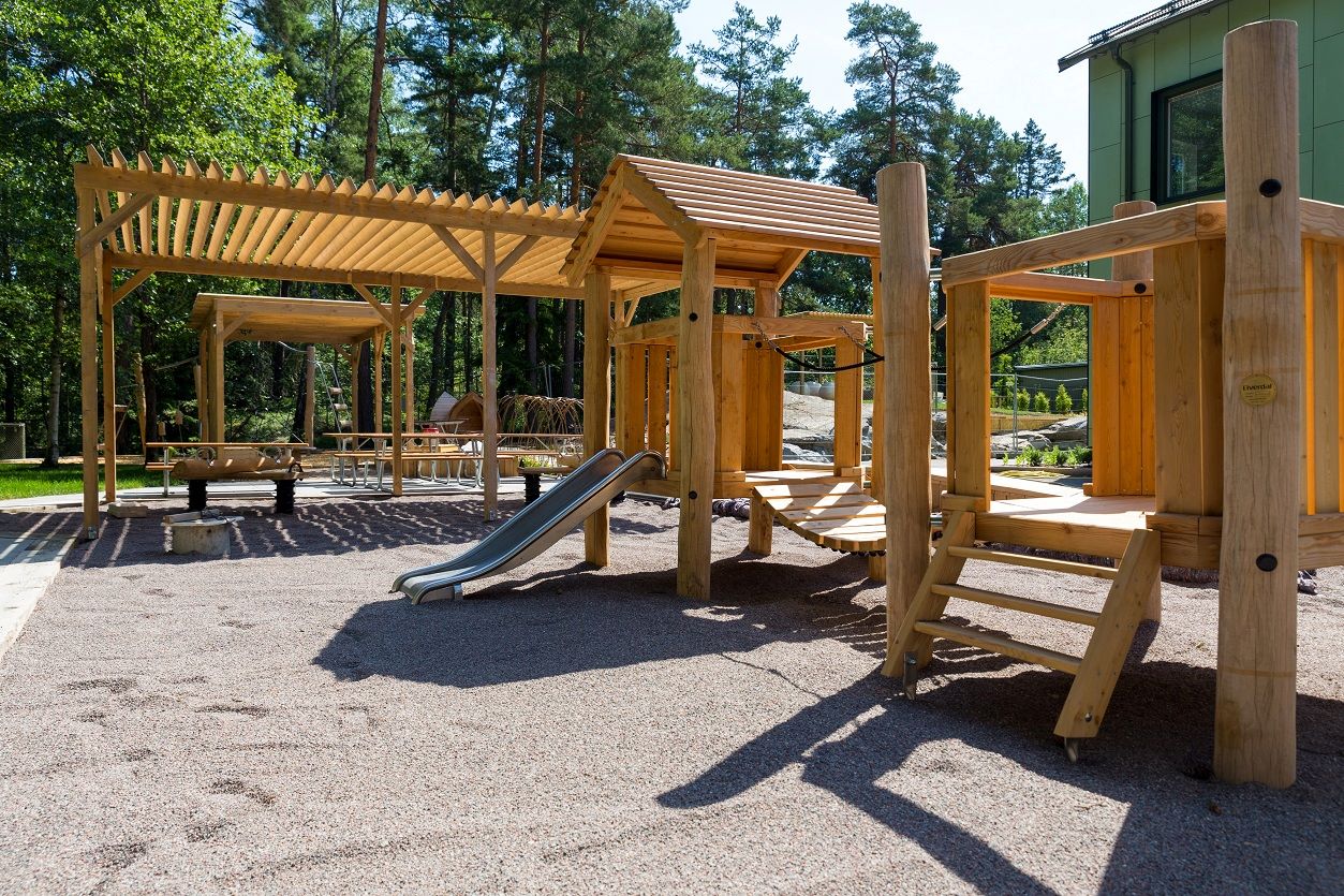 Gård med sittplatser och lekobjekt där man kan klättra och åka rutschkana.