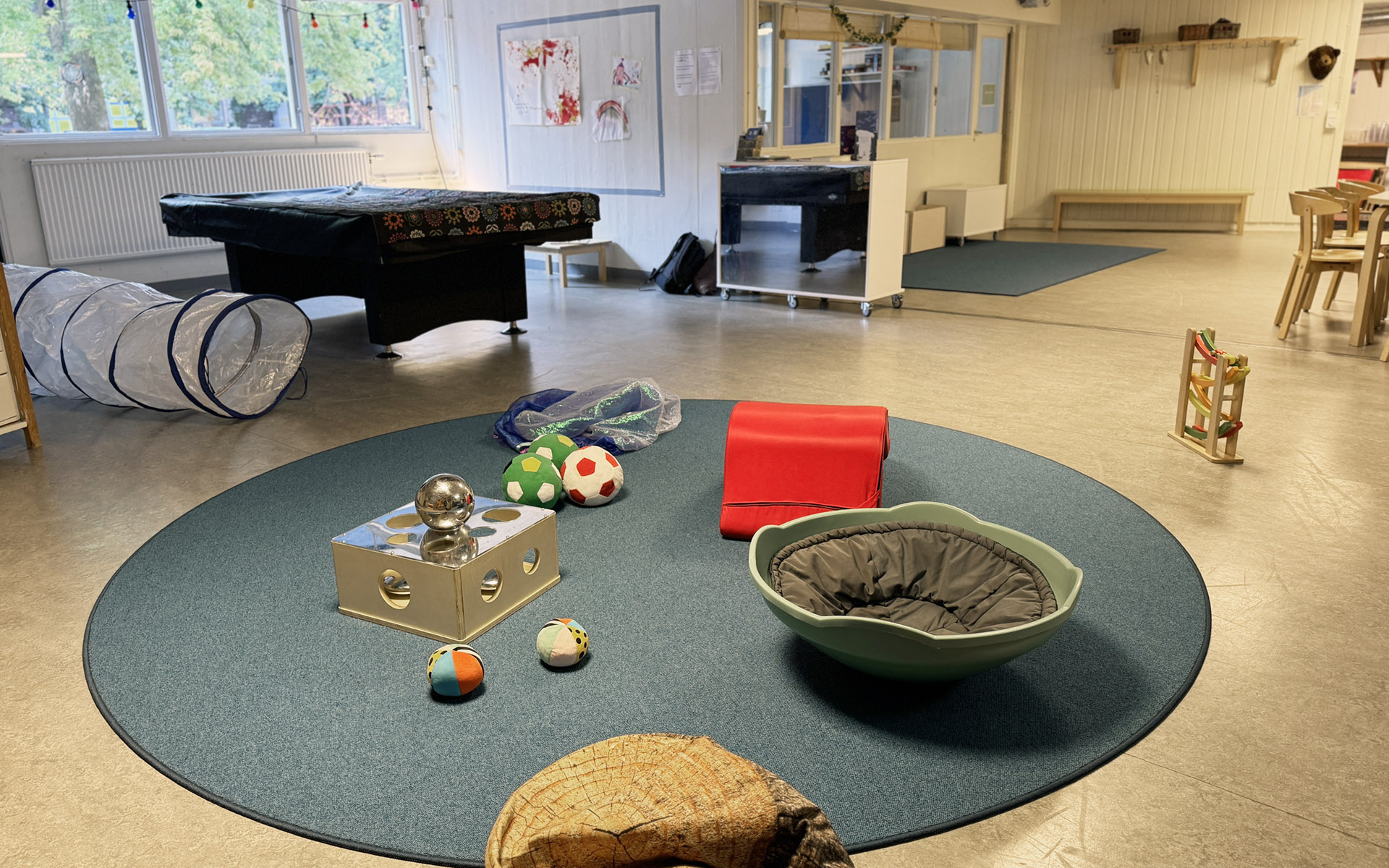 Ett rum med en rund lekmatta med bollar och andra leksaker på.