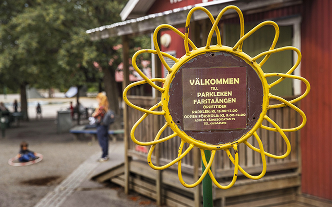 En skylt som er ut som en solros framför ett rött trähus