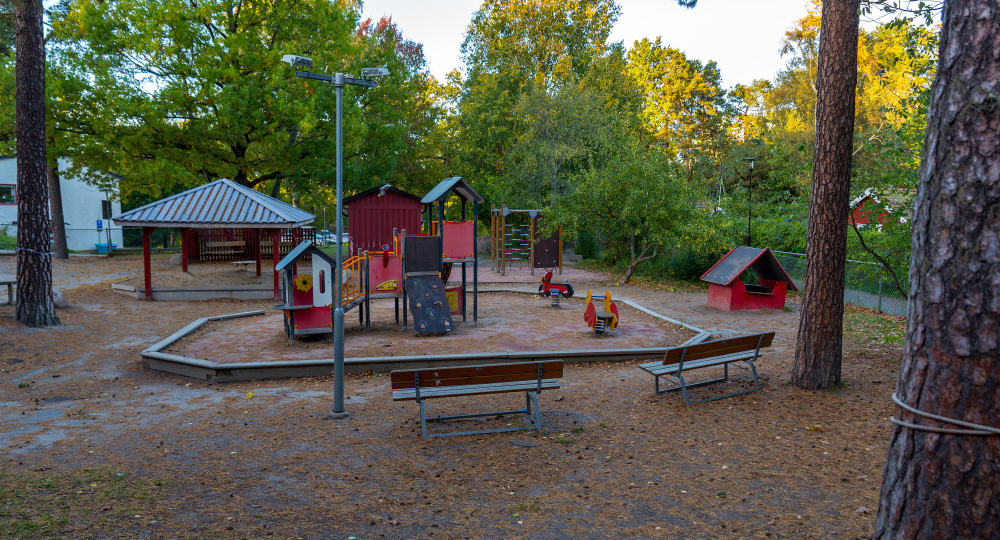 Skuggig lekplats omgiven av träd, foto.