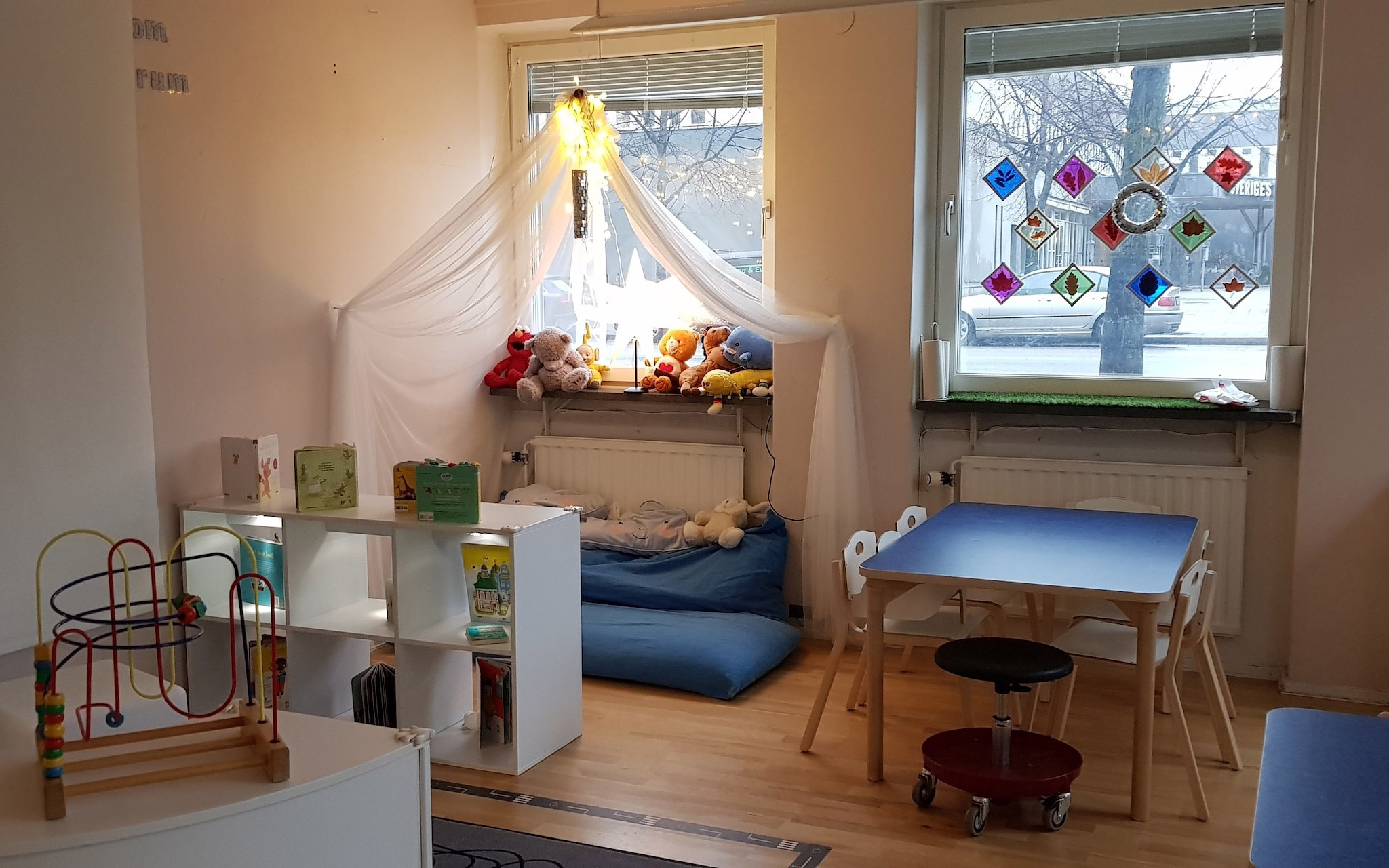 Lekrum med leksaker och gosedjur, kuddar, bord och stolar.