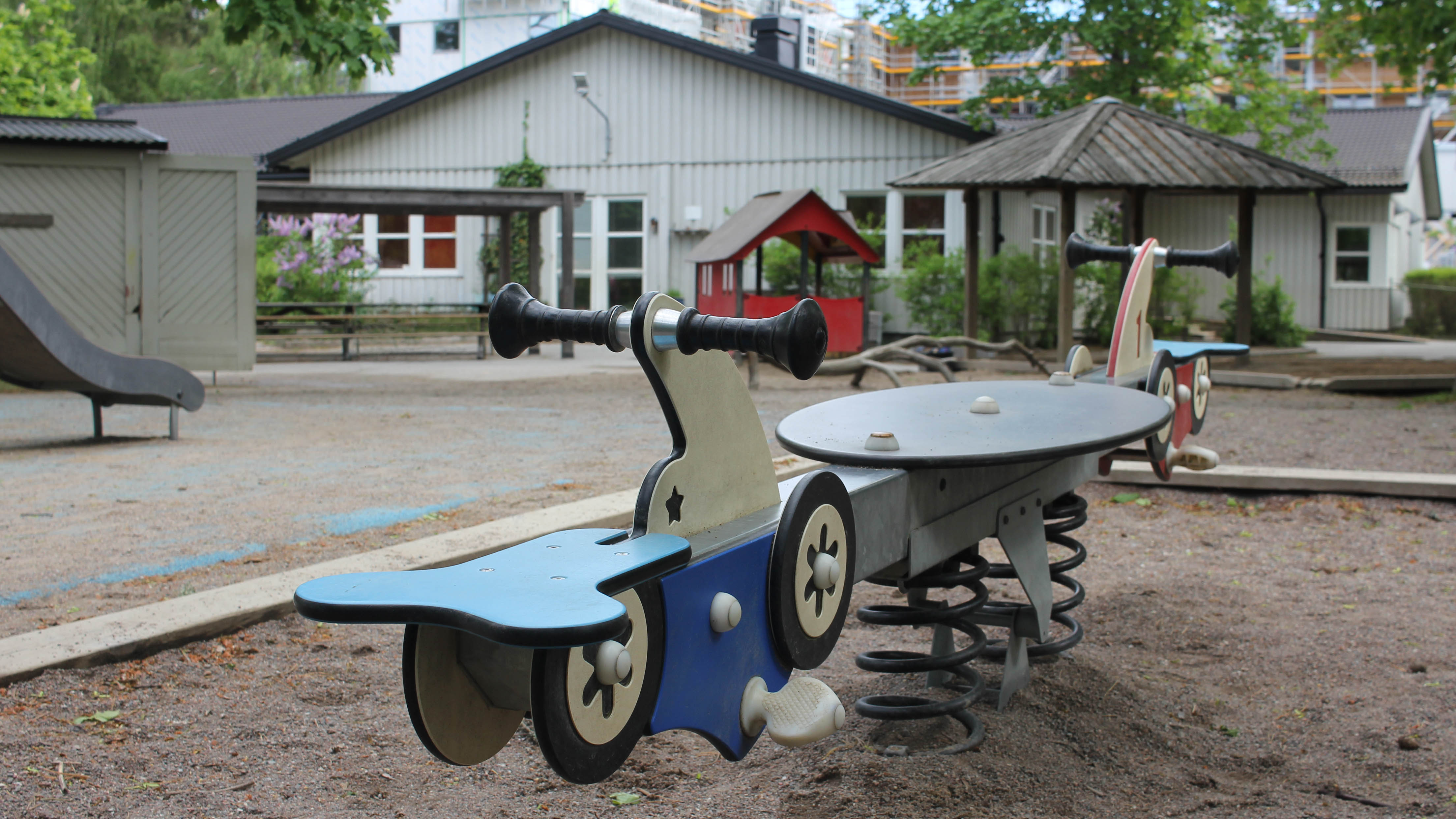 Blå bilgunga på stor utegård framför Mumindalens förskola.