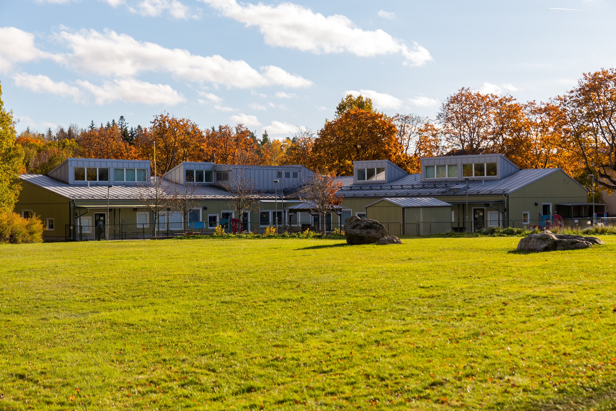 Byggnad med skog i bagrunden och ett öppet fält utanför gården till byggnaden