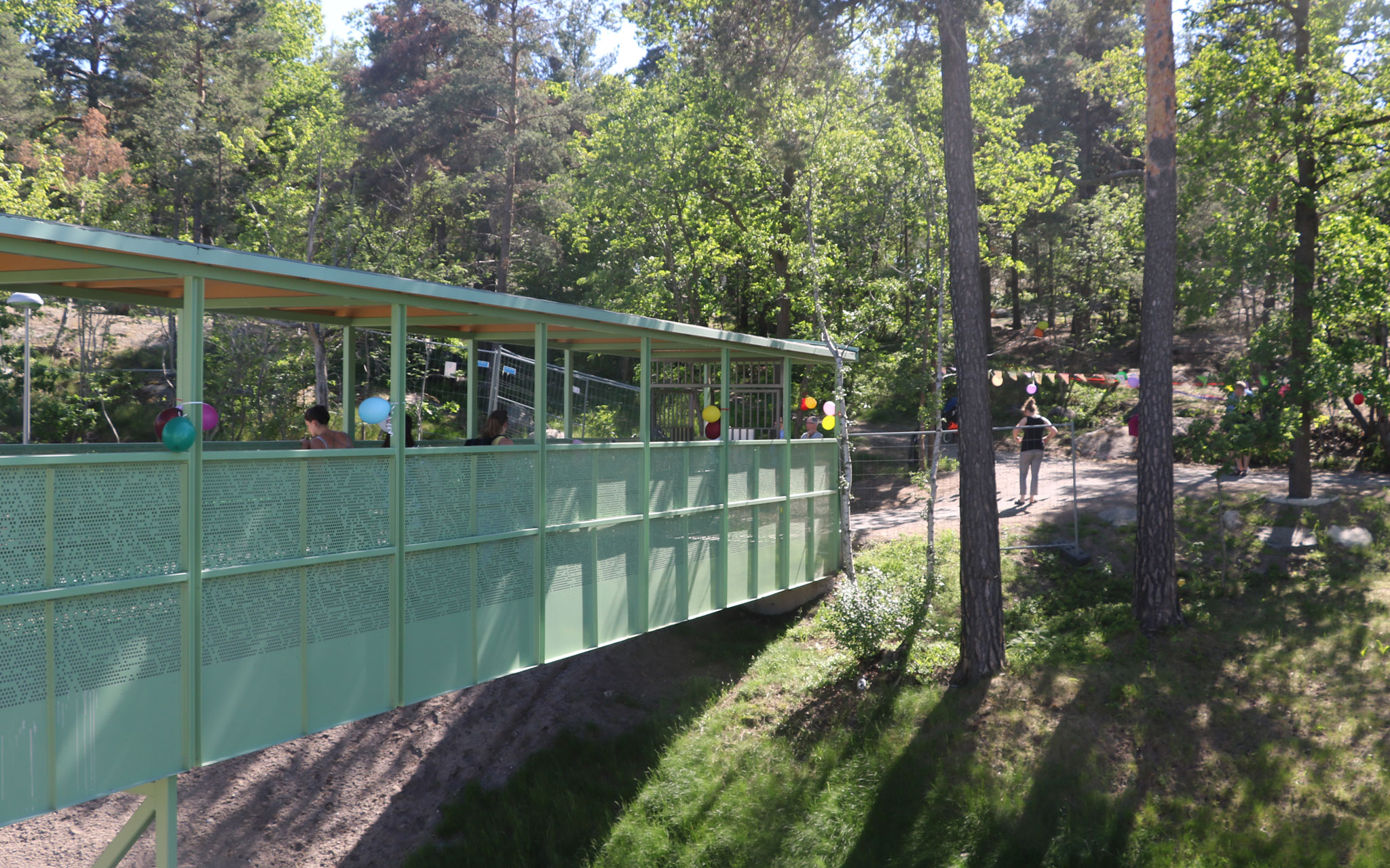 Spång från förskolan till naturmark med träd.