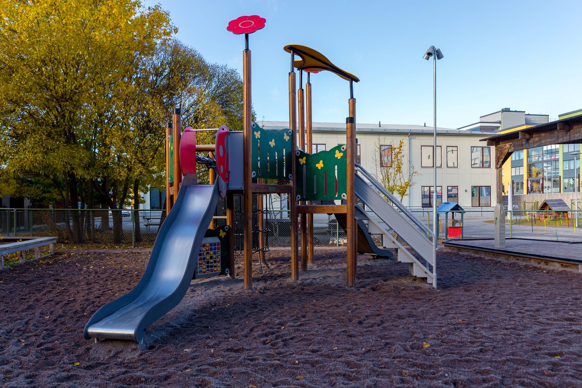 Gård med klätterställning, sandlåda och asfalt med stor byggnad i bakgrunden.