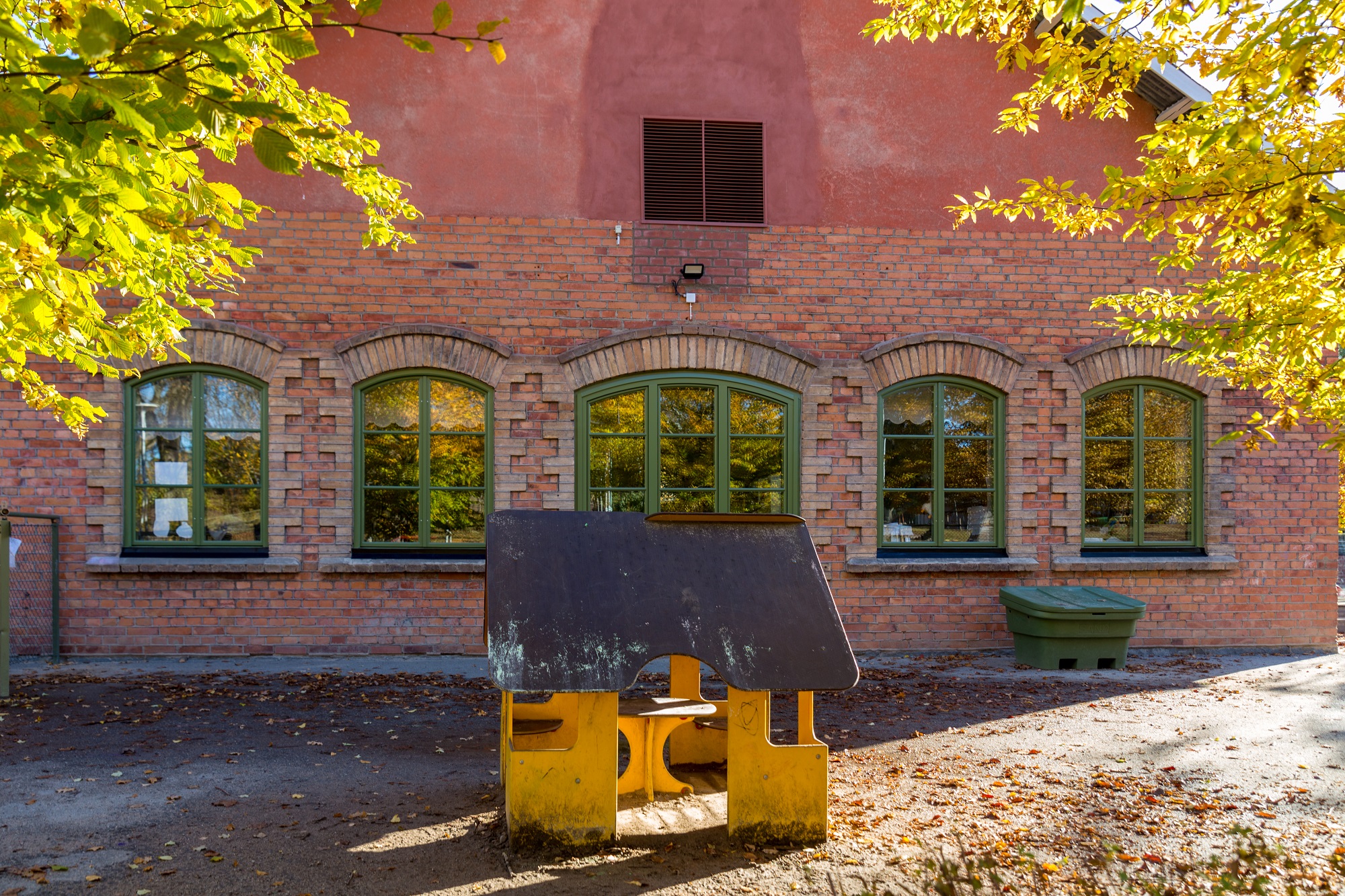 Byggnad med träd och lekobjekt utanför