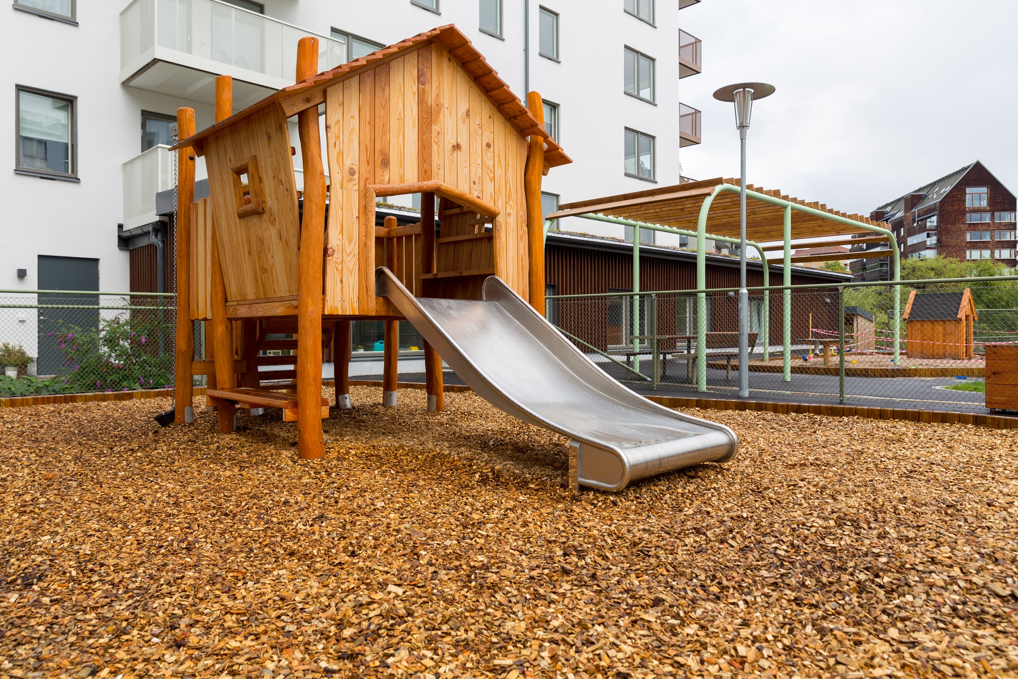 Del av innergård till flerbostadshus med ett klätterhus med rutschkana.