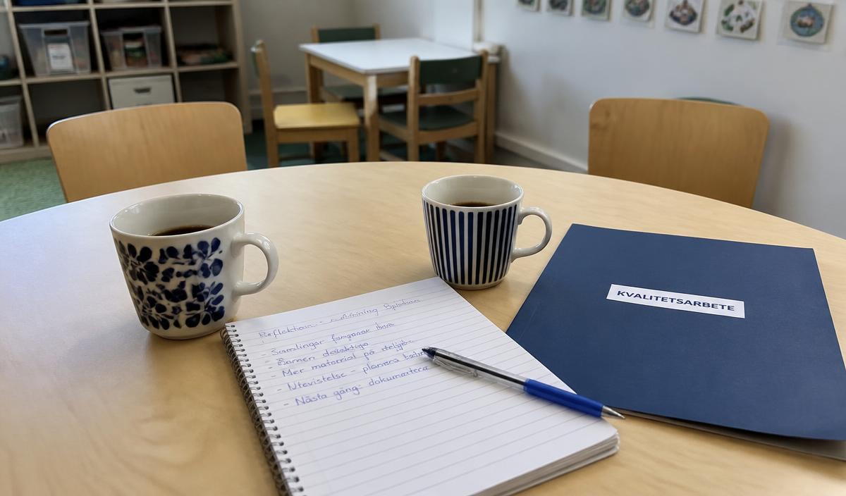 Ett litet mötesbord på en förskola med två kaffekoppar, ett anteckningsblock och en pärm